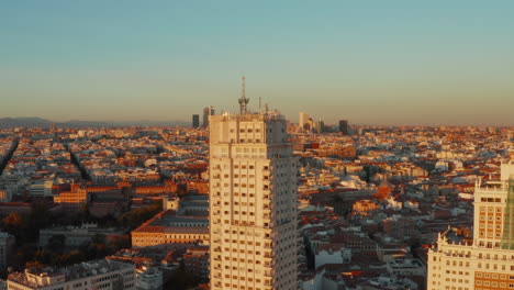 Toma-Elevada-Del-Desarrollo-De-La-Ciudad-Iluminada-Por-La-Brillante-Luz-Del-Atardecer.-Torre-De-Madrid-Edificio-Histórico-De-Gran-Altura-En-Primer-Plano.