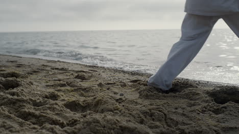 closeup man feet stepping on sand training karate. athlete exercising on beach.