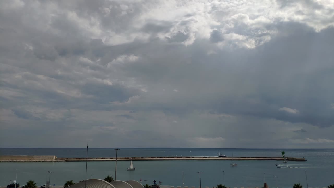 꽤 많은 구름과 뒤에 빛나는 태양이 있는 밝은 날 바르셀로나의 항구 지평선의 시간 경과