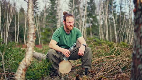 portrait of a hiker drinking water from a glass bottle in a forest. static shot