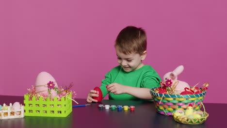 young toddler focusing on decorating easter eggs with stamps and watercolor