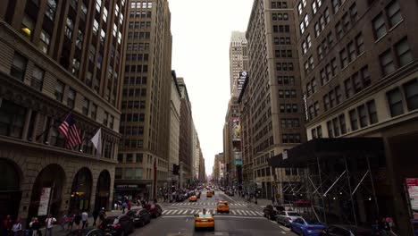 establishing moving shot of iconic new york city street with taxis and american flags