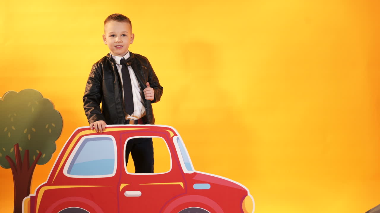 Little boy with a bright red car on a yellow background in the studio. Happy children.