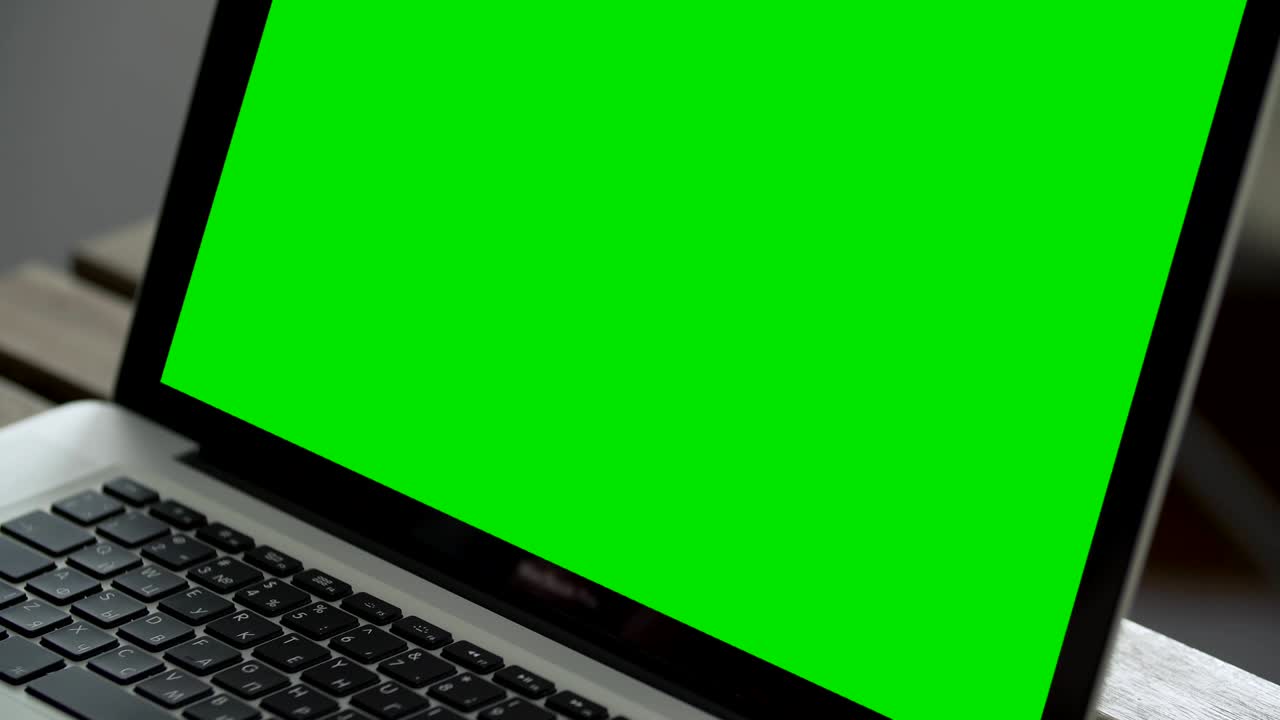 mano de un hombre trabajando en una computadora portátil escribiendo en el teclado. pantalla verde de cerca