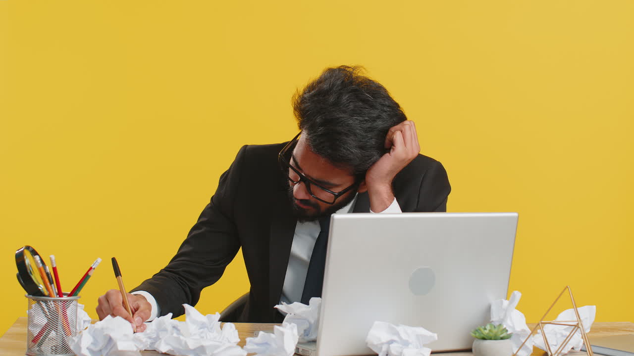 Angry furious man working at home office throwing crumpled paper having nervous breakdown at work