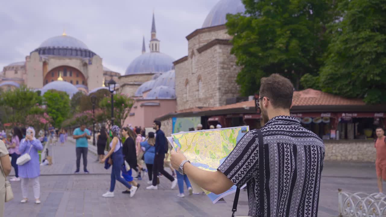 turista de homem olhando para o mapa de papel contra a mesquita hagia sophia.