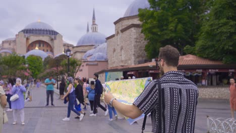 Man-tourist-looking-at-paper-map-against-Hagia-Sophia-Mosque.