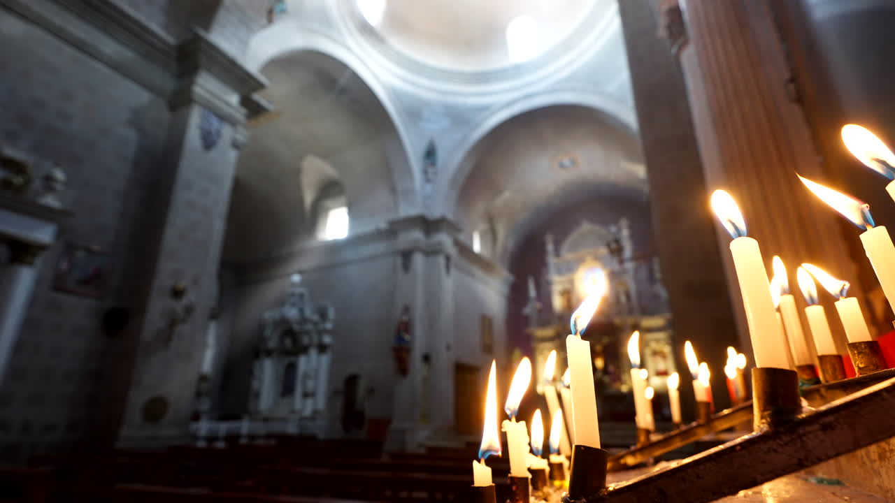 Candele accese che tremolano all'interno di una chiesa storica scarsamente illuminata