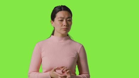 studio portrait of woman thinking standing against green screen