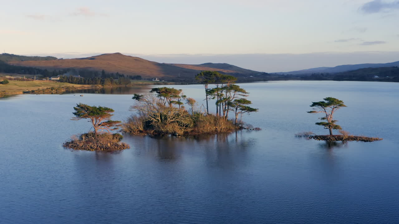 Aerial orbit pullback of a calm Connemara lake with blue waters and Irish hills, showcasing unspoiled beauty, Galway, Ireland