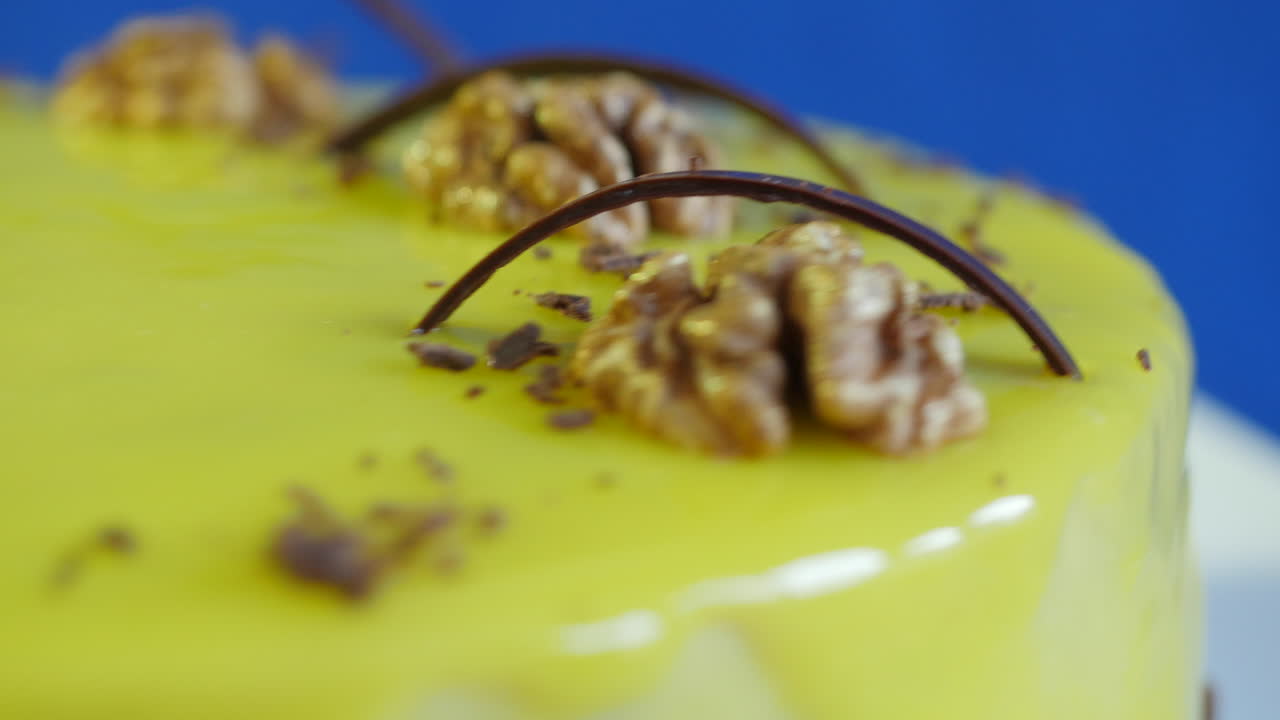 крупный план красиво украшенного желтого глазурного торта с грецкими орехами и шоколадом