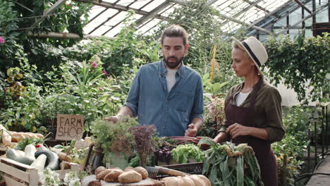 two coworkers in a farm shop organizing products, man points to a vegetable box