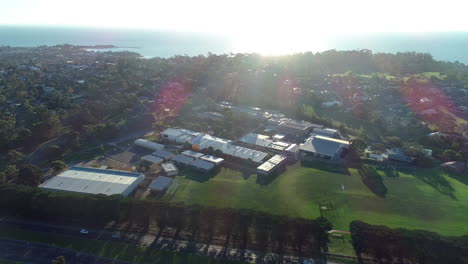 aerial perspective moving parallel to mornington high school showing suburbs and ocean in the background late afternoon.