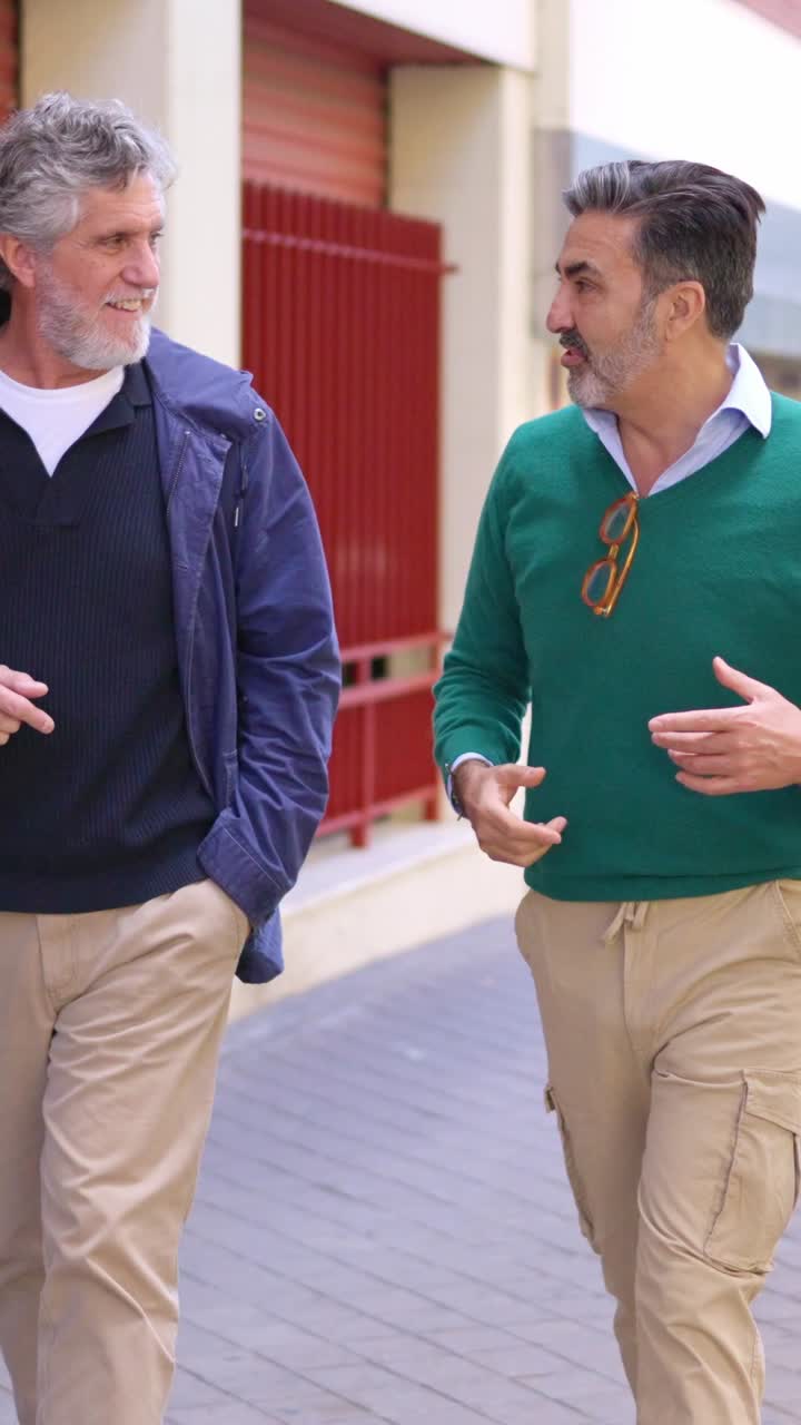 Dos hombres maduros caminando y hablando en una calle de la ciudad