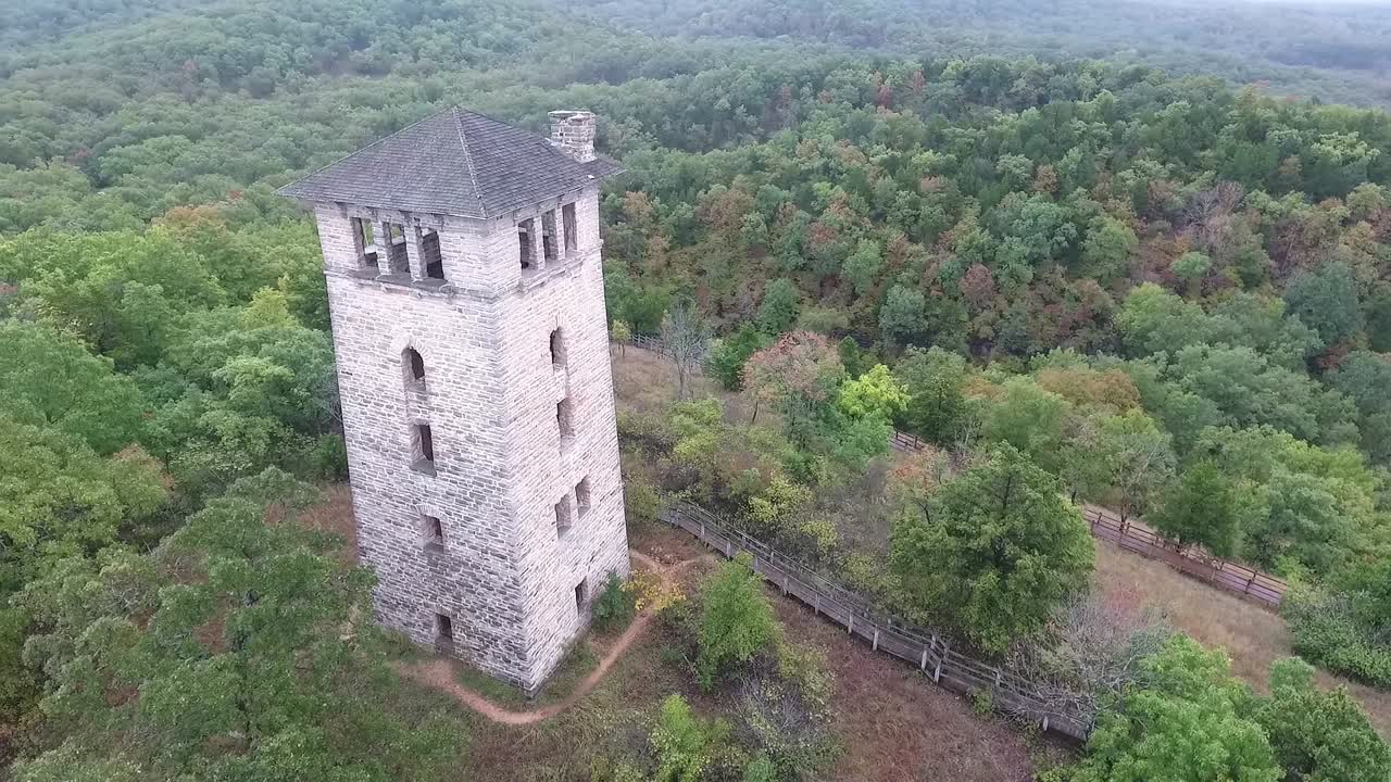 Drone doing a 60 degree rotation around watchtower at Haha Tonka state park with epic scenery of autumn colored trees and sky in background