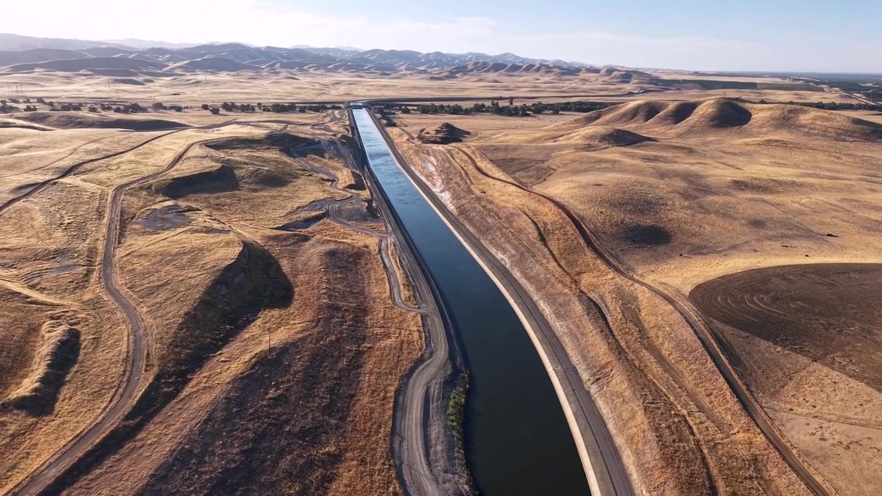 Acqua che scorre attraverso i deserti dei canali dell'acquedotto della California. Ampio paesaggio di un fiume artificiale agricolo che fornisce acqua a terreni agricoli per l'irrigazione nelle zone rurali.