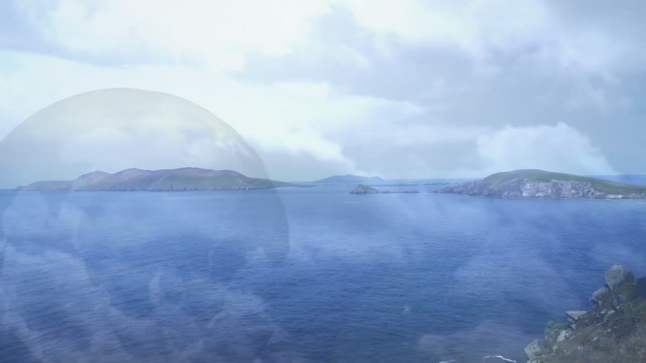 Calm ocean expanse stretching past green islands and rocky outcrop, drifting under overcast sky