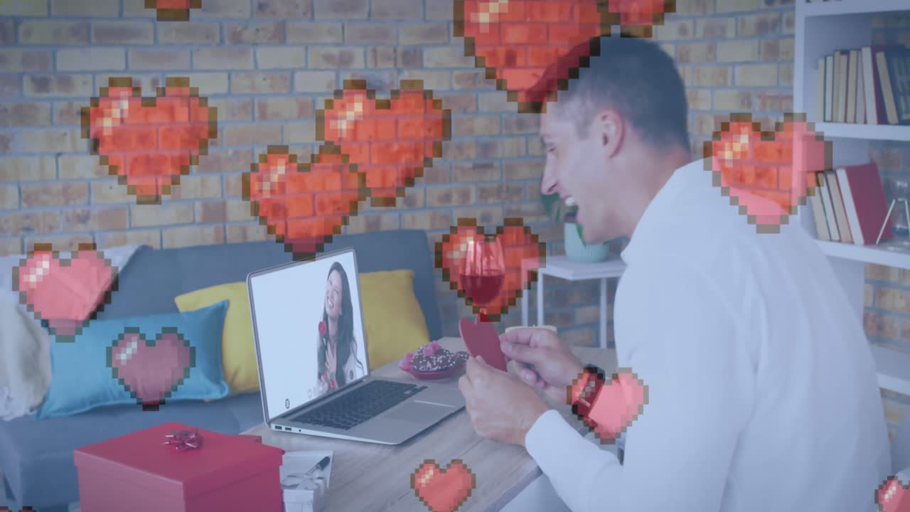 corazón pixelado sobre hombre caucásico sosteniendo cartel en forma de corazón mientras hace una videollamada en una computadora portátil