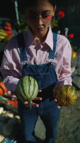 adolescente sosteniendo calabazas en el mercado de un granjero