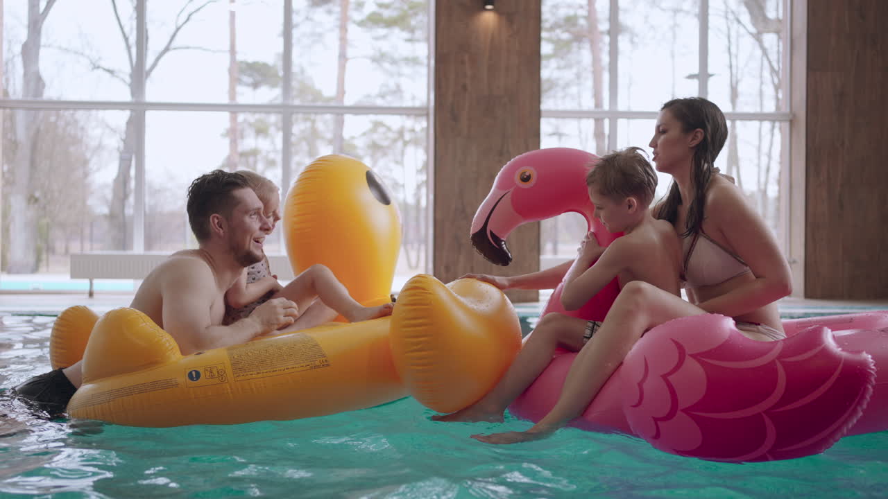 visitantes en el centro de bienestar familiar madre padre e hijos están nadando en círculos inflables y jugando