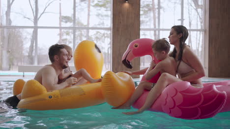 visitors in family wellness center mother father and children are swimming on inflatable circles and playing