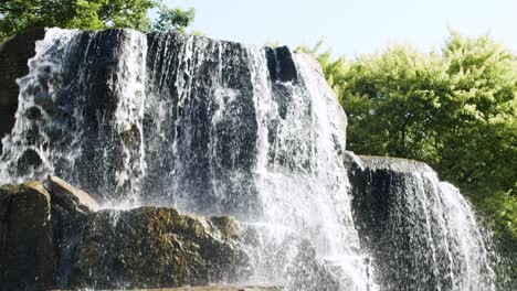 the top of a small waterfall in a green forest