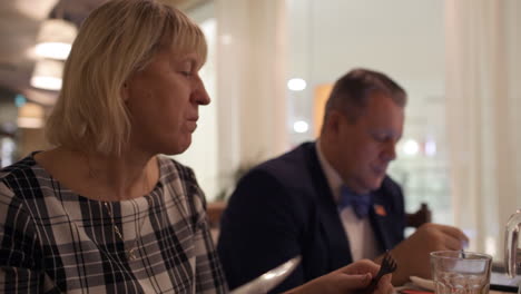 Woman-having-meals-and-man-talking-on-business-using-pad