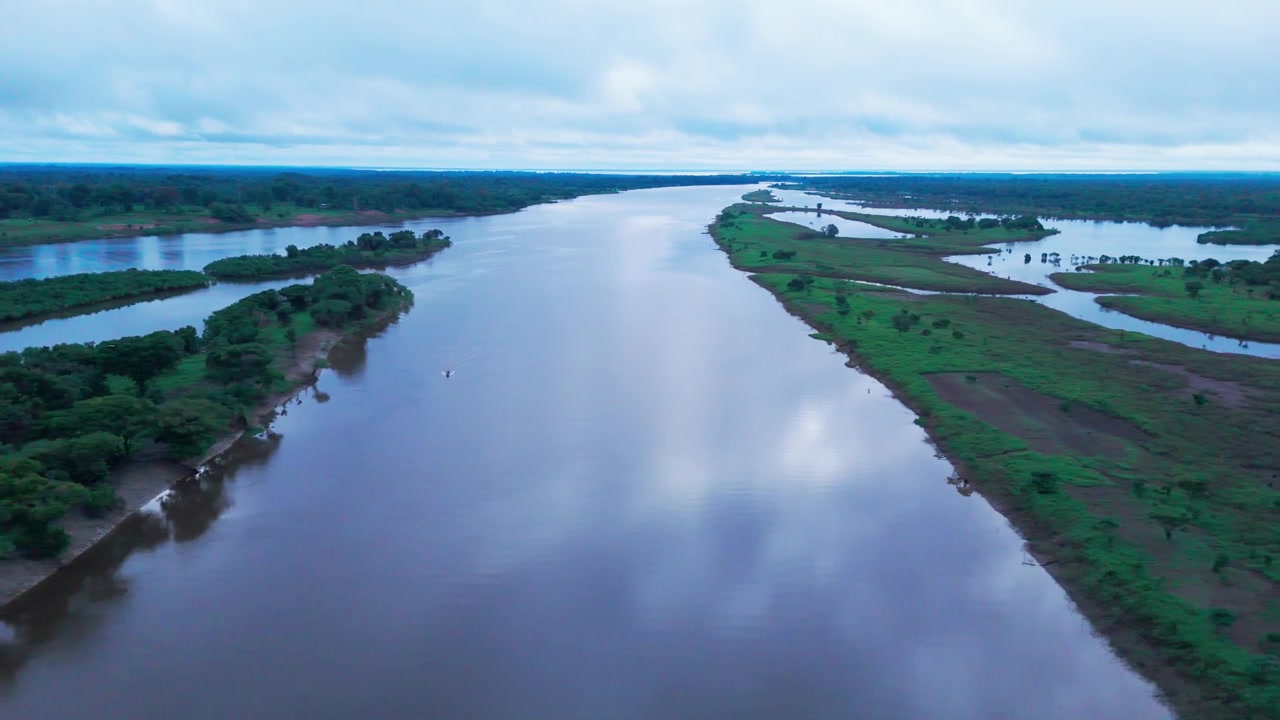 Snoede vandløb, der strømmer gennem tropiske landskaber i den brasilianske Amazonas om aftenen, viser vandveje, frodig vegetation og skyrefleksioner, filmisk luftfoto