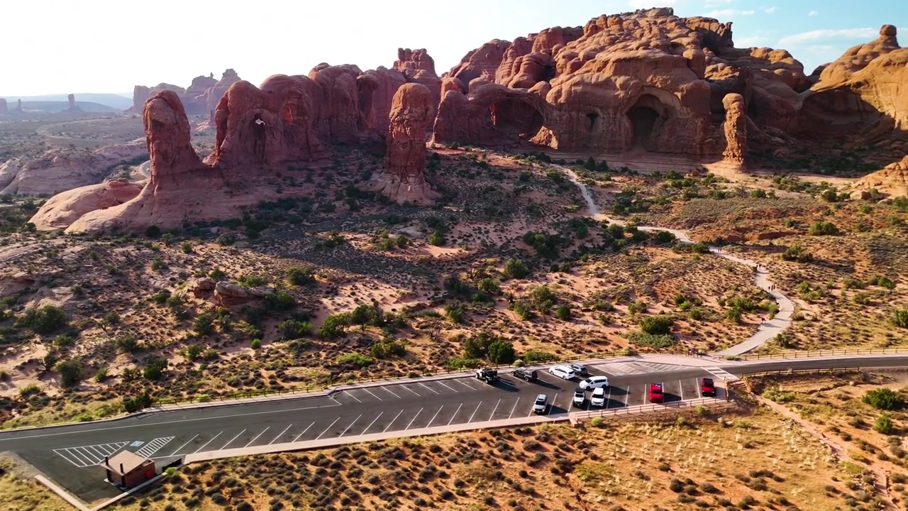 Splendido filmato stock del Parco Nazionale di Arches, USA, durante un pomeriggio luminoso. La luce solare brillante illumina le maestose strutture di arenaria rossa e il paesaggio desertico sotto un cielo azzurro limpido.