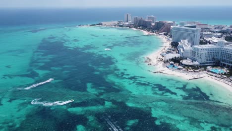 Aerial-view-of-Cancun-hotel-zone-with-blue-Caribbean-sea,-white-beach-and-jet-skis-riding-on-water