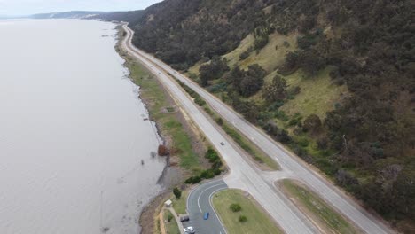 drone voando sobre uma auto-estrada de 4 pistas do lado do lago e uma montanha de área de descanso do outro lado