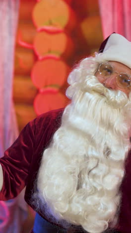 happy santa claus is dancing near the christmas tree with sparklers. vertical video