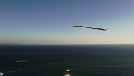 cometa janggan con cola larga volando en el cielo por encima del mar en bali