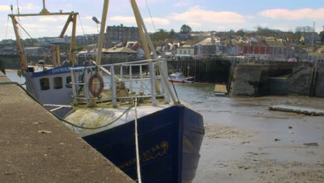 Padstow-fishing-boat-moored-up-on-dock-amongst-shop-front-Wide-shot