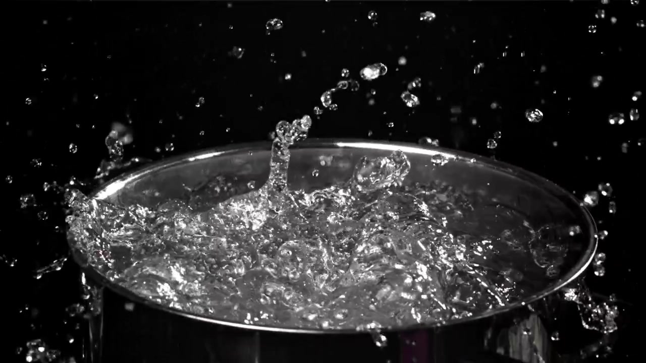 Primo piano al rallentatore di acqua bollente che schizza in una pentola