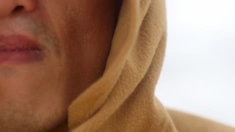 extreme close up of chinese asiatic male face with dehydrated lips wearing a sand colour hood robe