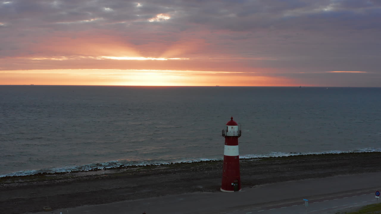 The lighthouse of Westkapelle during a bright orange sunset, with a lot of wind