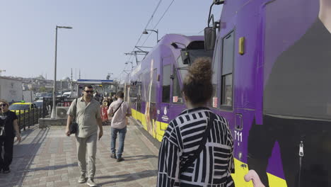 person walking alongside a moving tram on galata bridge, with views of the city and waterfront in the background