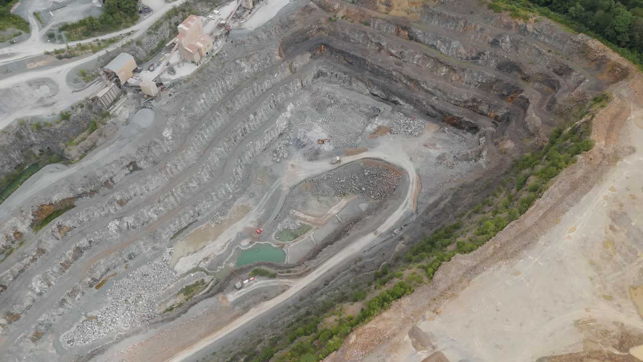 Drone of expansive aggregate mining operation with visible machinery on the quarry floor, showcasing the scale and industrial activity
