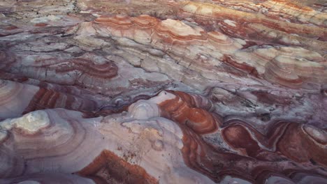 aerial 4k drone flyover view of bentonite hills, utah, at golden hour with colorful mars like landscape