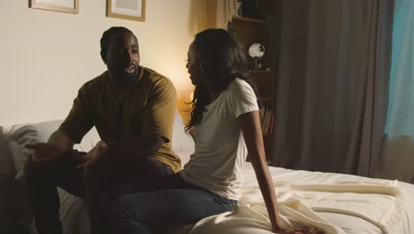 couple at home sitting on bed at night having argument 1