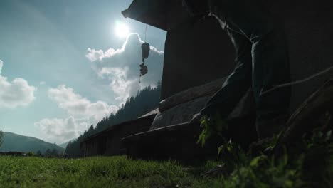 Silhouette-of-millennial-male-backpacker-adventurer-walking-by-rural-cabin-in-slow-motion-during-the-day