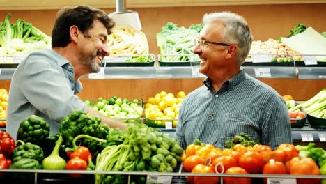 two men laughing while shopping for produce