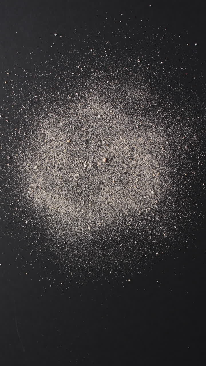 Vertical video of close up of sand grains and copy space on black background