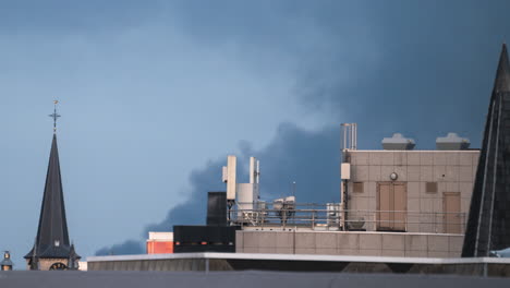 Pan-over-the-roofs-as-the-light-fades-while-smoke-blows-in-Antwerp,-Belgium