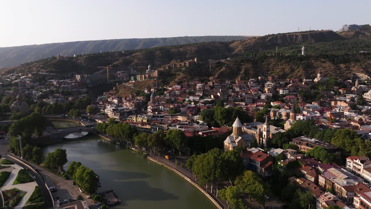 Drone Ascends Above Tbilisi Bridge of Peace on Summer Day in Georgia.