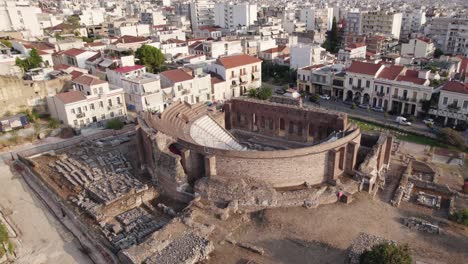 Drone-arc-shot-of-Roman-Odeon-ancient-amphitheater-and-cityscape-view-of-Patras