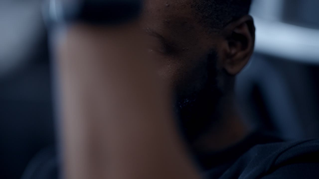A fit african american man performing lat pull-downs in gym