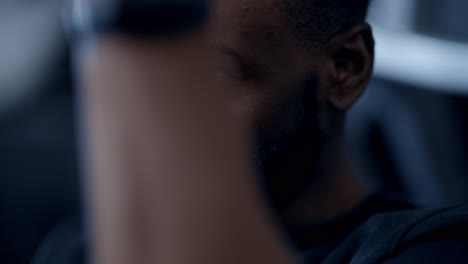 a fit african american man performing lat pull-downs in gym