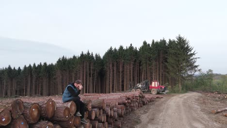 lonely lumberjack sitting alone in sorrow after cutting tree in forest causing deforestation, global warming and climate change on planet earth